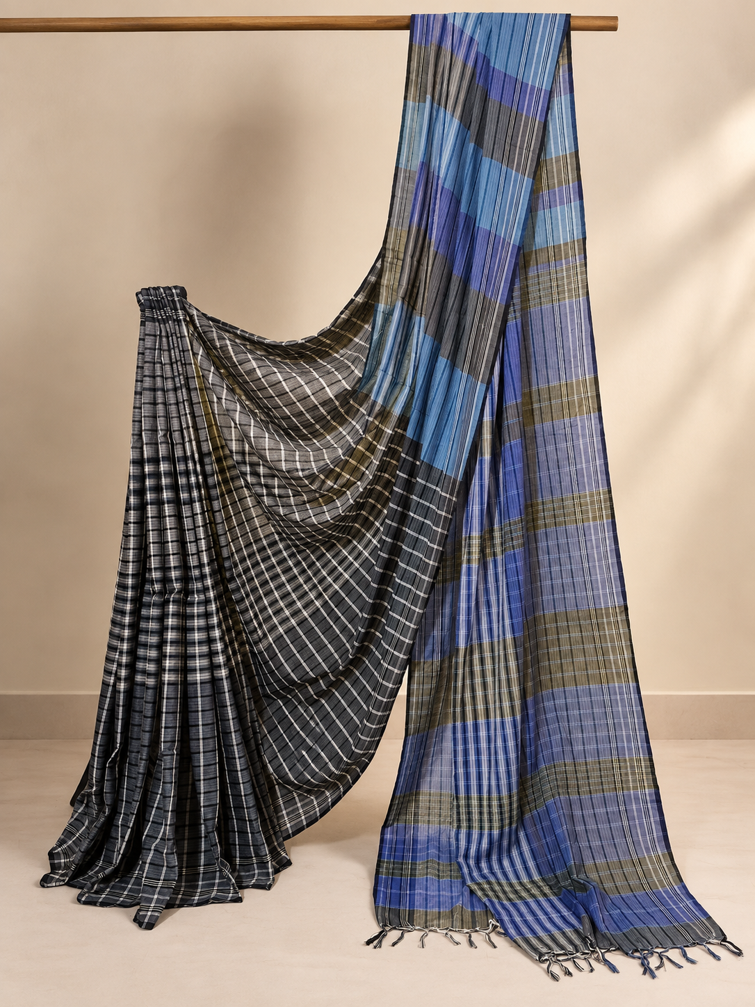 Blue, black, olive and grey handloom Gamchha saree featuring checked and striped patterns with a contrasting pallu and handcrafted tassels, displayed in a studio setting.