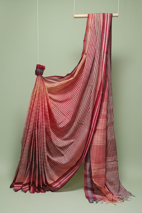 Red and white checkered saree draped over a wooden rod against a white background