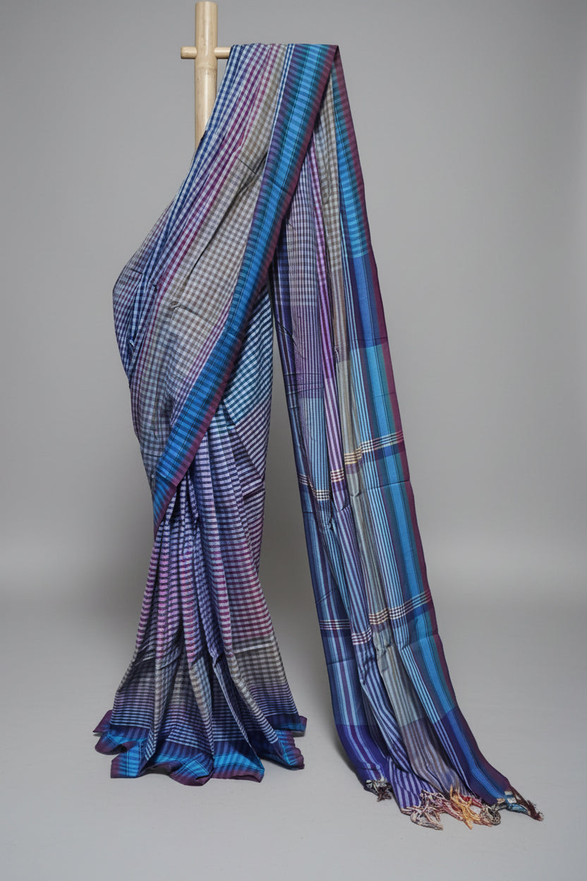 Blue and purple checkered saree draped over a wooden stick against a white background