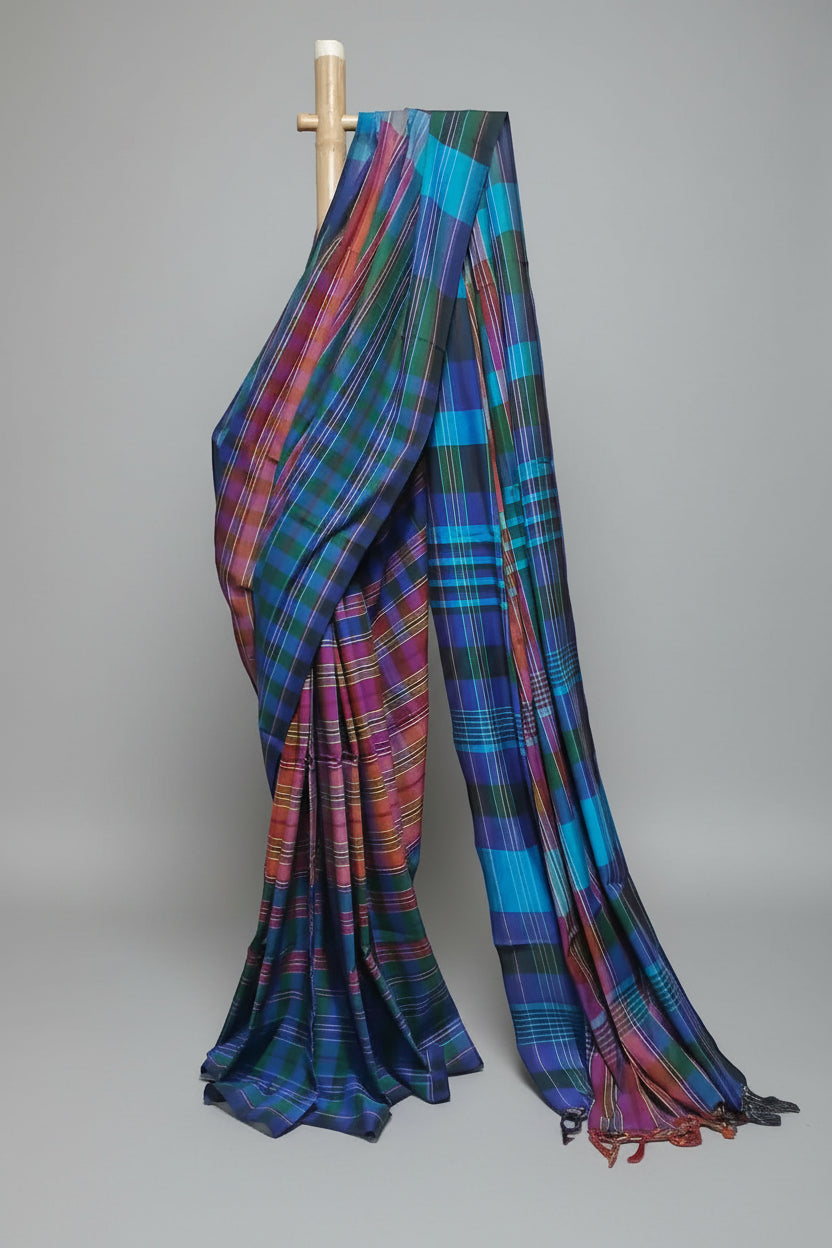 Multicolored plaid saree draped over a wooden rod against a white background