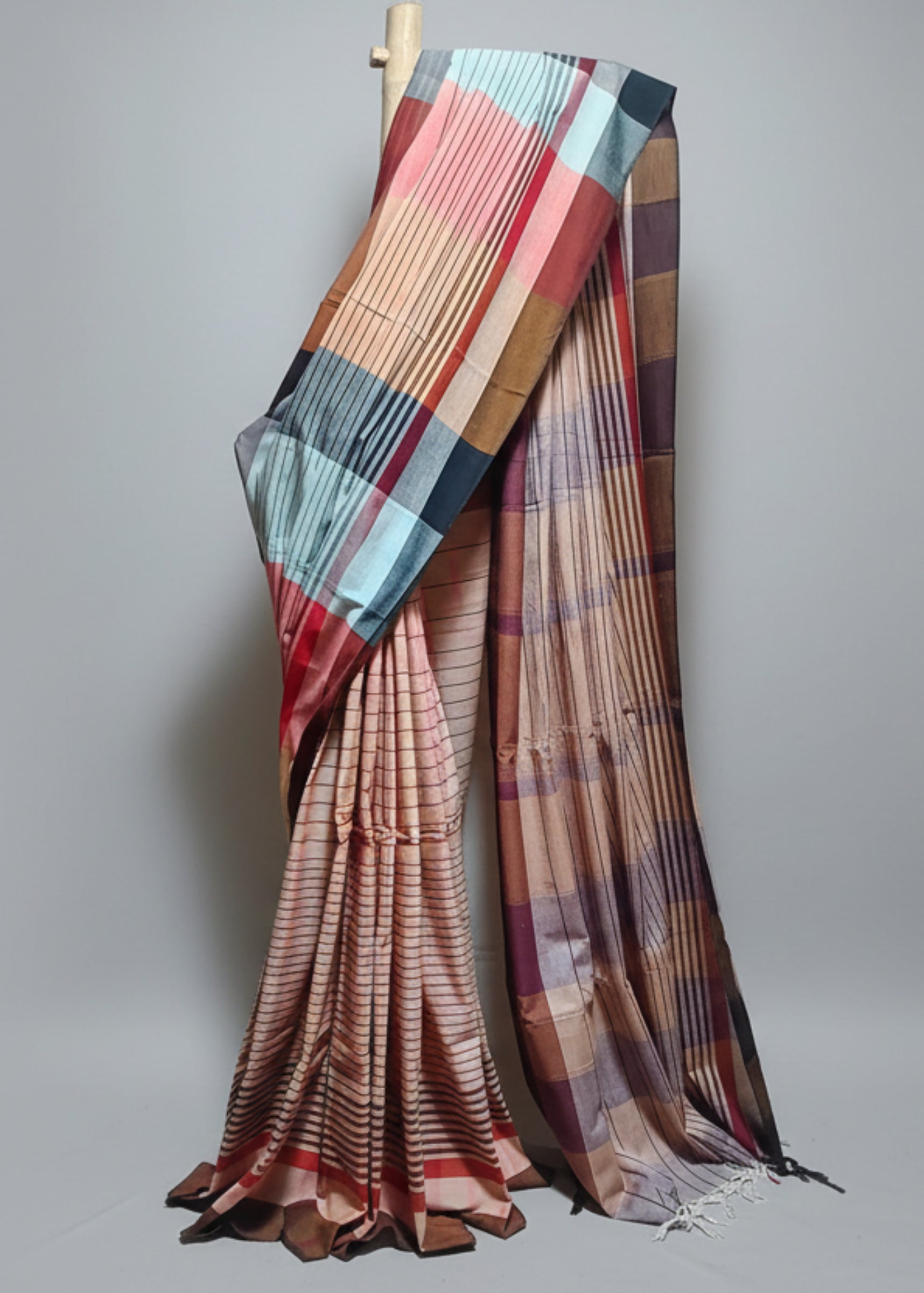 Colorful saree draped over a chair against a white curtain background
