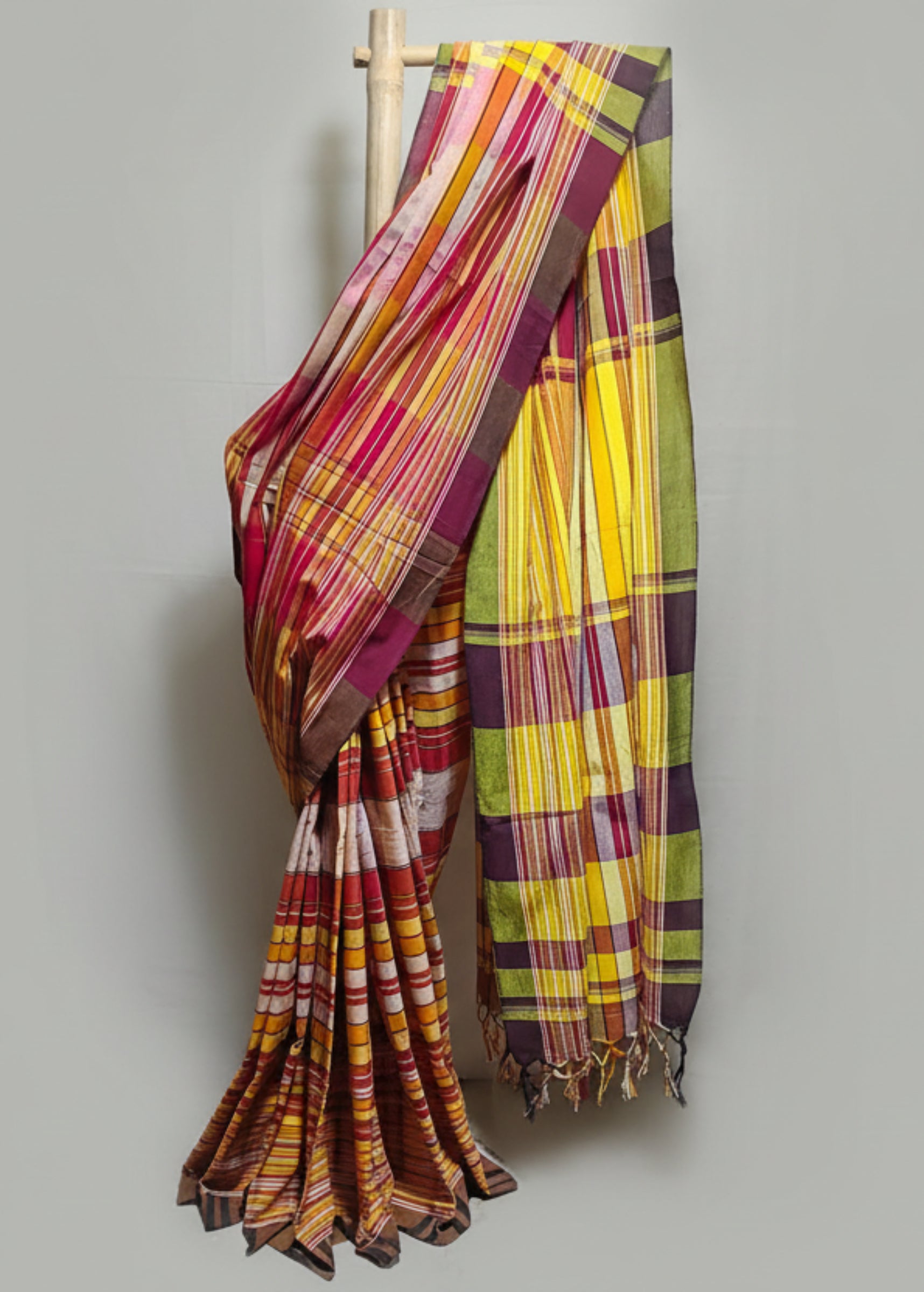 Colorful plaid Saree draped over a wooden rod against a white background