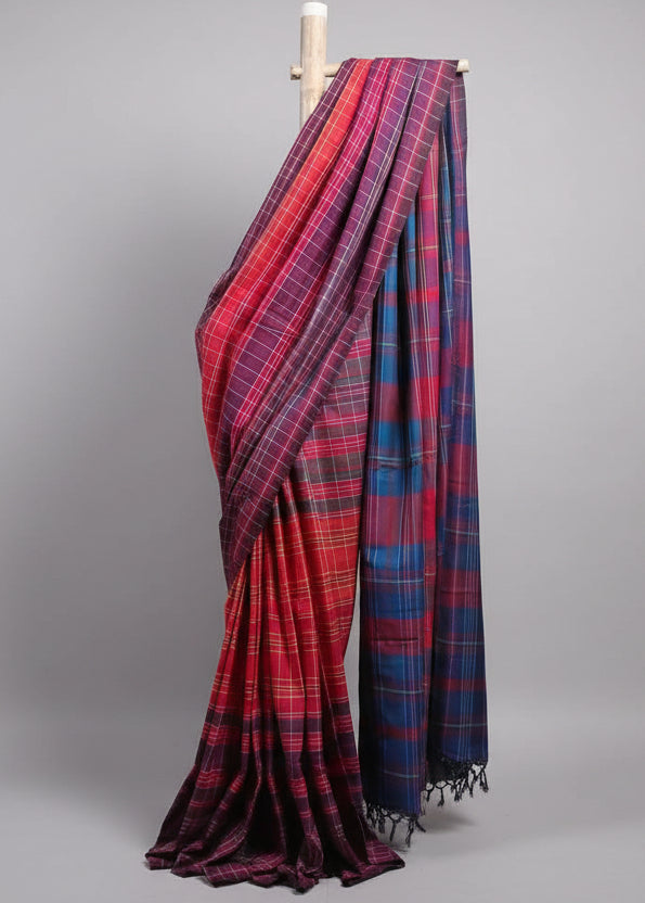 Red and blue plaid fabric draped over a wooden rod against a white curtain background.