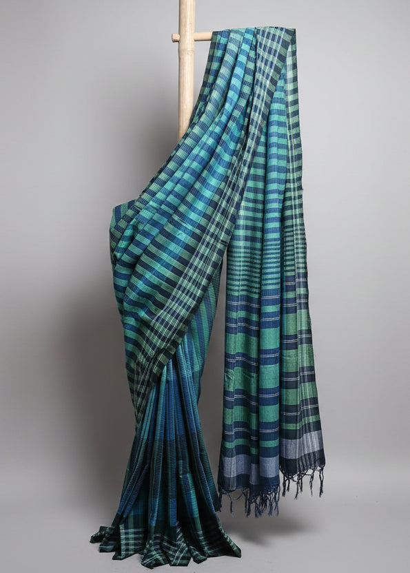Blue and green plaid fabric draped over a wooden rod against a white curtain background