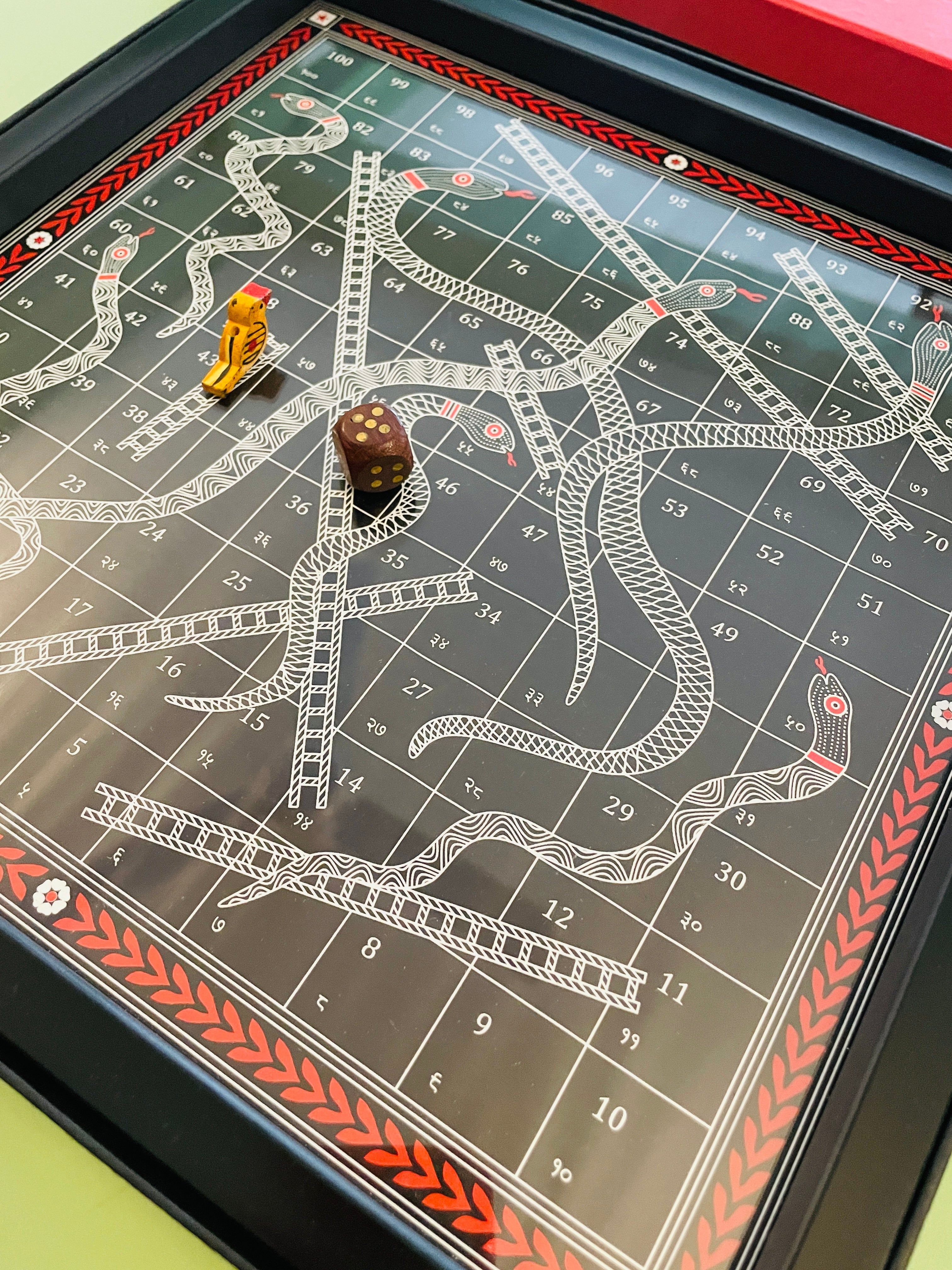 Handcrafted Snakes and Ladders board game with traditional folk-inspired artwork